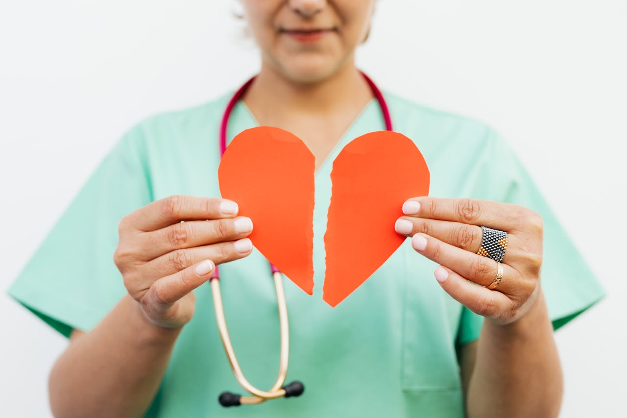 Home Nurse holding a torn paper heart symbolizing emotional or heart health care.
